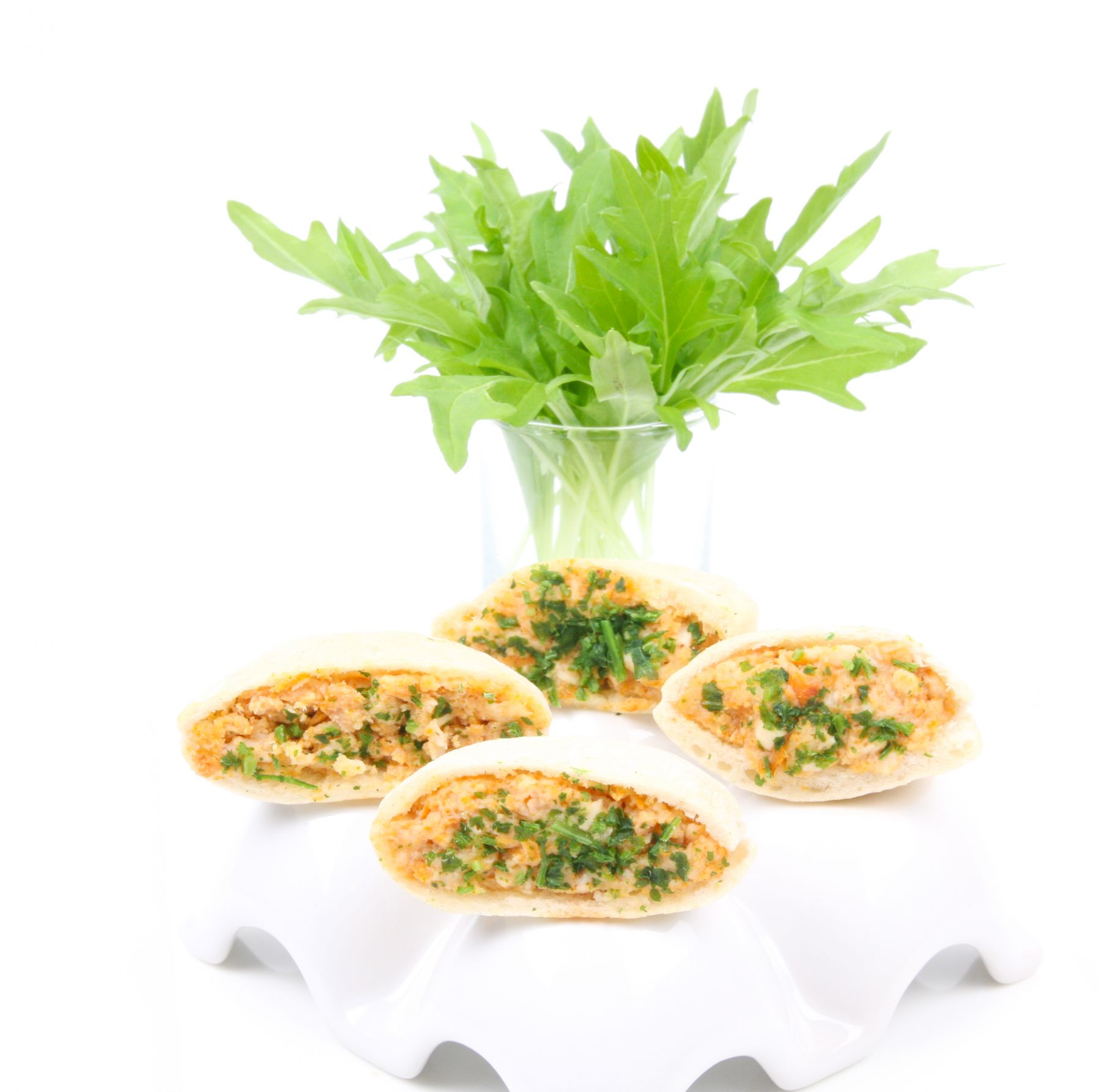 Dix-sept pièces de COCKTAIL STREET FOOD, à la fois sucrées et salées, sont disposées avec art sur un plateau blanc, avec des herbes fraîches dans un verre à proximité. L'ensemble se détache sur un fond blanc immaculé.