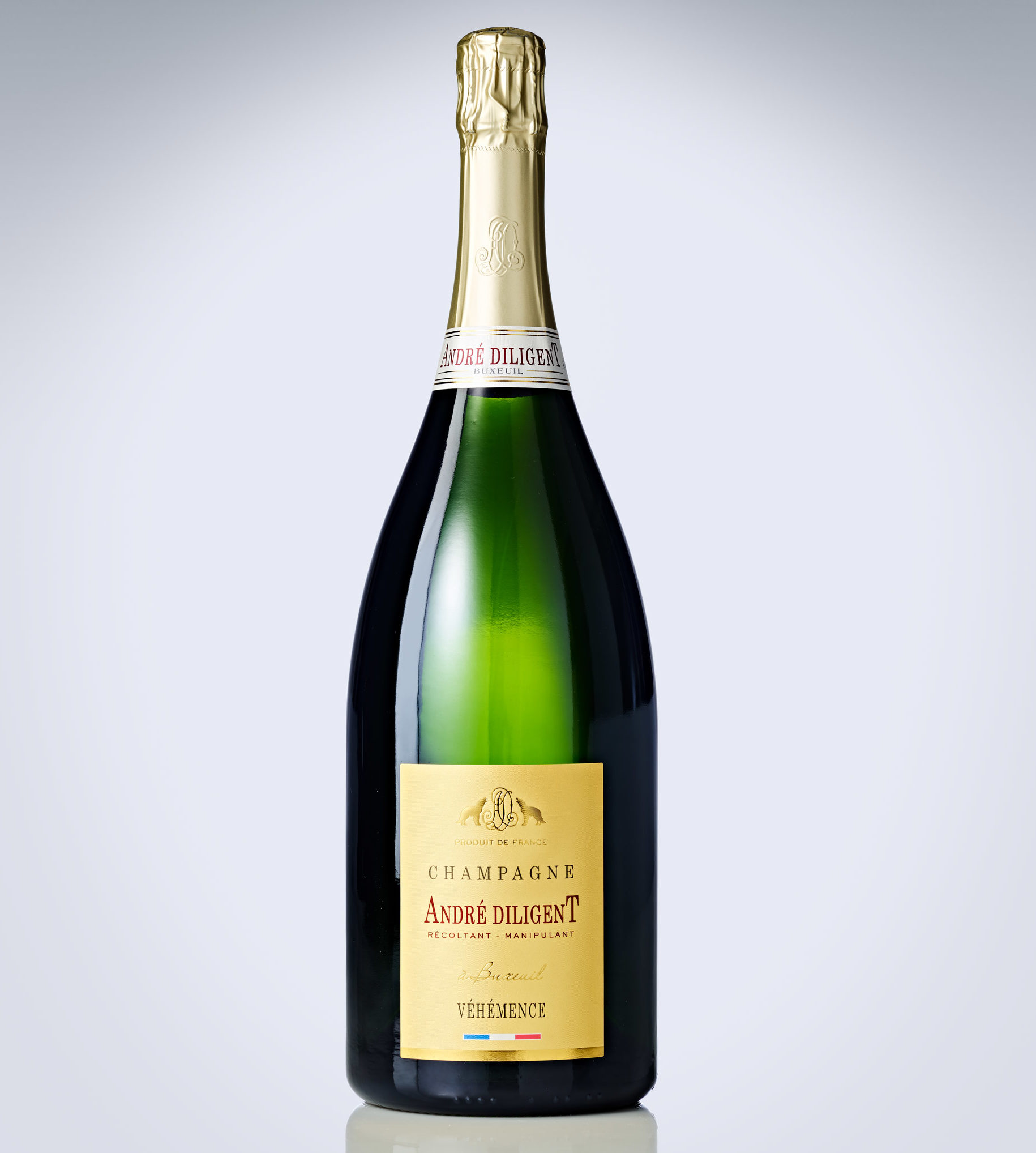 Une bouteille de CHAMPAGNE ANDRÉ DILIGENT (Brut Blanc 75cl) avec un bouchon et une étiquette en feuille d'or, sur un fond de dégradé clair. L'étiquette porte les mentions "Champagne André Diligent" et "Véhémence".