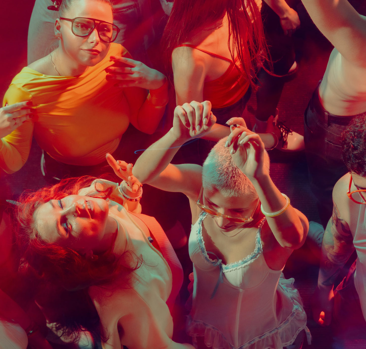 Un groupe de jeunes adultes dansent étroitement ensemble sous un éclairage rouge et rose vibrant fourni par DJ PROFESSIONNEL AVEC SONO & LUMIERES, certains les mains levées et les yeux fermés, profitant pleinement de la musique et de l'ambiance de la fête.