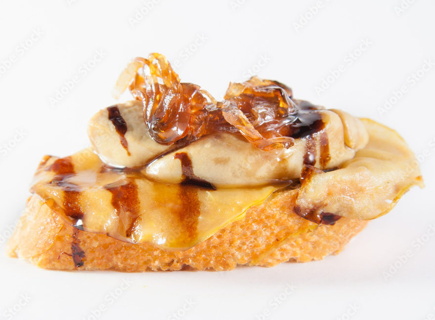 Une tranche de pain grillé garnie d'ANIMATION BAR A FOIE GRAS, d'oignons caramélisés et d'un filet de glaçage balsamique foncé, sur fond blanc.