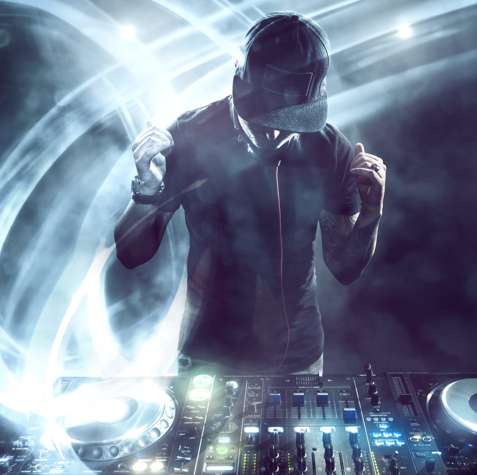 Le DJ PROFESSIONNEL AVEC SONO & LUMIERES dynamise la scène, en mixant derrière la console en casquette et au casque, entouré de lumières et de fumées tourbillonnantes pour une ambiance de fête vibrante.