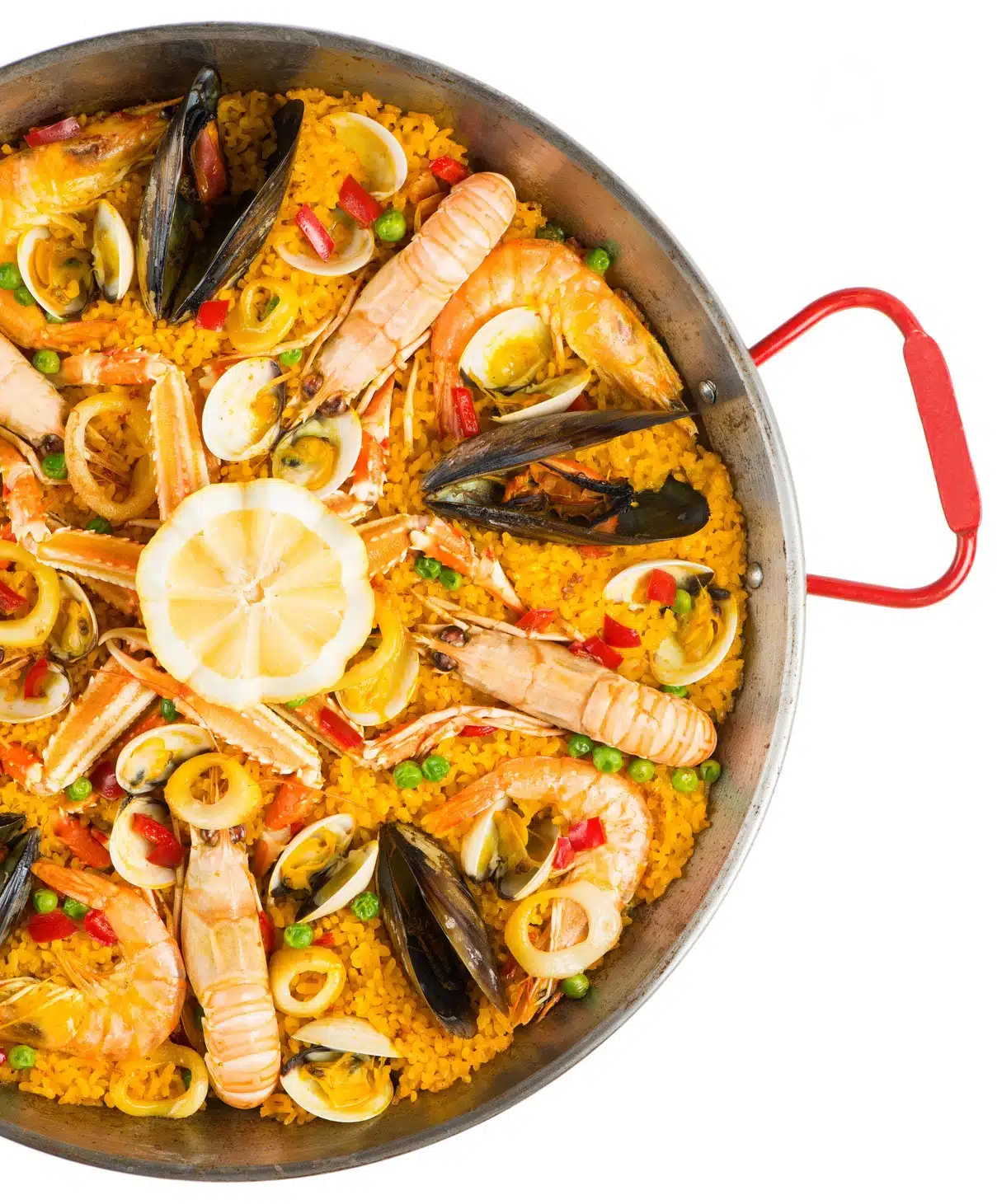 Vue de dessus de PAËLLA PARTY (400g/pers & Matériel fourni), montrant du riz, des moules, des crevettes, des palourdes, des petits pois, du poivron rouge et des tranches de citron dans une casserole à poignée rouge sur fond blanc.