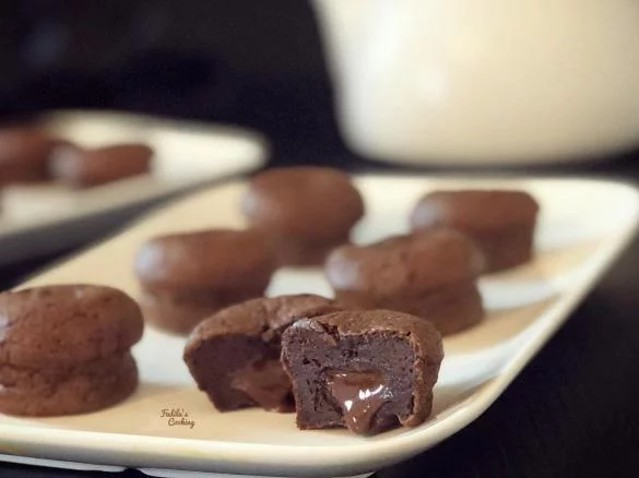 Une assiette présente le COCKTAIL STREET FOOD (17 pièces salées et sucrées), avec un biscuit au chocolat découpé révélant un centre gluant et d'autres biscuits bien rangés à l'arrière-plan.