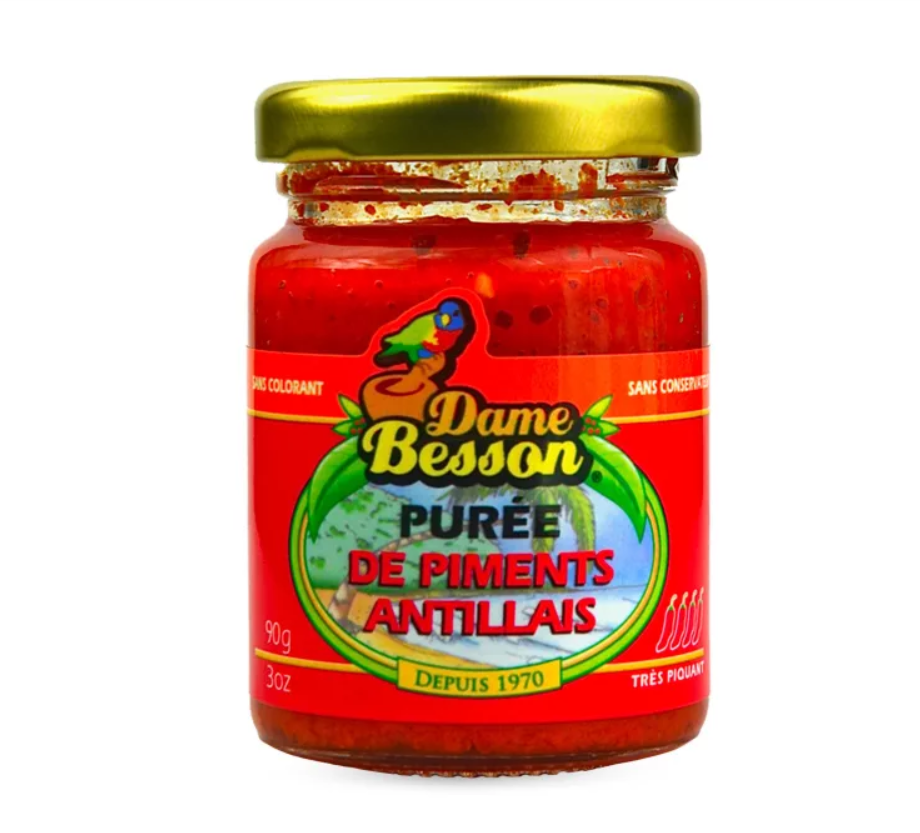 Un pot de 90 grammes de PIMENT ANTILLAIS, une purée de piment très épicée des Caraïbes avec une étiquette rouge, un couvercle doré et un logo illustré, fabriquée depuis 1970.
