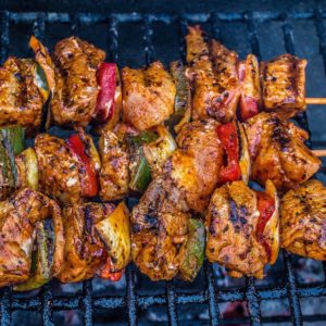 NOS VIANDES POUR L'ANIMATION BARBECUE (prix par pers) propose des brochettes de viande assaisonnée, juteuse et carbonisée, accompagnée de poivrons verts et rouges et d'oignons, grillés à la flamme nue pour une expérience barbecue savoureuse.
