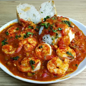 BOUDIN AU CRABE (Barquette de 20 pièces, 40g à l'unité) servi sur une table en bois, accompagné de riz blanc, d'herbes hachées et de deux tranches de pain.