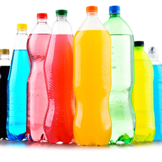 Une rangée de bouteilles de SOFTS À VOLONTÉ POUR VOTRE ÉVÉNEMENT aux couleurs vives - rouge, orange, jaune, vert, bleu et noir - avec des bouchons assortis se dresse sur un fond blanc.