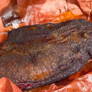 LE BRISKET SIGNATURE PAR STEPHAN "L'art du feu et du temps" est une grande poitrine de bœuf fumée, assaisonnée, sur papier de boucherie brun-rouge, luisante de jus et dotée d'une écorce sombre et savoureuse.