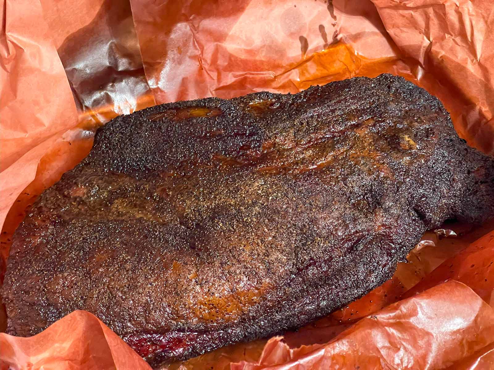 LE BRISKET SIGNATURE PAR STEPHAN "L'art du feu et du temps" est une grande poitrine de bœuf fumée, assaisonnée, sur papier de boucherie brun-rouge, luisante de jus et dotée d'une écorce sombre et savoureuse.