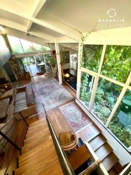 Le salon moderne et aéré de LE LOFT ART FEELING (93170) BAGNOLET est doté de grandes fenêtres offrant une vue imprenable, de planchers en bois, de canapés confortables, de tapis, de plantes d'intérieur pour la chaleur, d'un escalier descendant et d'une lumière naturelle abondante.