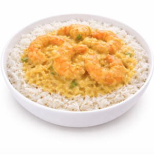 Un bol de riz blanc cuit à la vapeur garni de CREVETTES ROYAL KORMA (300 g), un curry de crevettes jaune crémeux avec plusieurs grosses crevettes disposées sur le dessus.