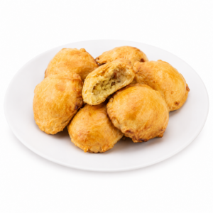 Une assiette blanche sur laquelle sont disposées sept pâtisseries MINI PÂTÉ ANTILLAIS À LA MORUE de couleur dorée, dont l'une est entaillée, laissant entrevoir une garniture savoureuse.