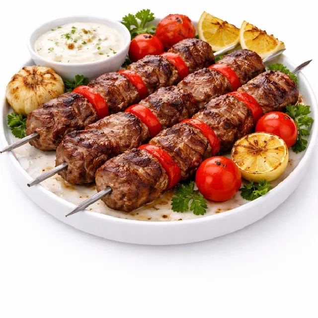 BROCHETTE DE BOEUF CUITE AU FEU DE BOIS (Barquette de 10 pièces) : dix brochettes de bœuf grillées au feu de bois, servies avec tomates et poivrons rôtis, citron, persil frais, ail grillé, tomates cerises et une sauce crémeuse.